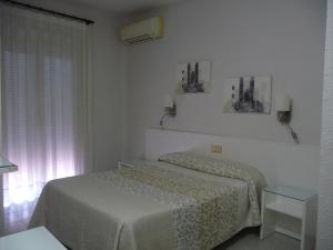 a white bedroom with a bed and a window at Hotel Goya in Lleida