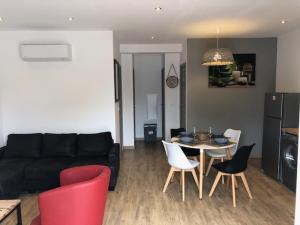 a living room with a black couch and a table and chairs at Résidence Casa Toga in Galeria