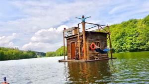 a person standing on top of a house on a body of water at Pływający Domek in Przywidz