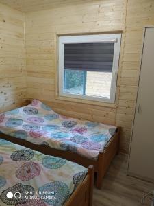 two beds in a room with a window at Domki na lipowej in Pastwiska