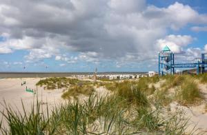 a beach with a building on it and the ocean at Hotel Pension Nordseewelle in Norddeich
