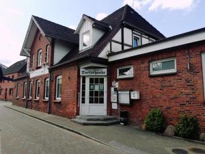 a brick building with a white door on a street at Hotel Dorfschänke in Büdelsdorf