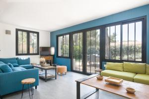 een woonkamer met blauwe en groene meubels en ramen bij Villa Ensoleillée in Sainte-Marie-de-Ré