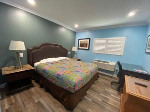 sypialnia z łóżkiem i niebieską ścianą w obiekcie Redondo Beach Motel - LAX w mieście Gardena