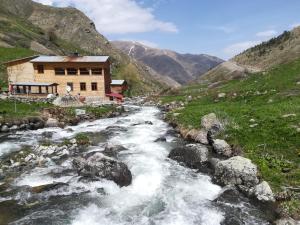 a house on the side of a river in a mountain at Kaçkar Pansiyon in Yaylalar