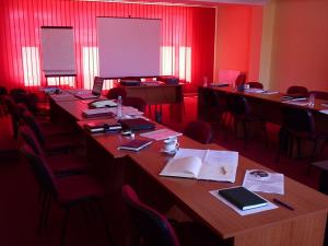 Habitación con mesas largas, sillas y paredes rojas. en Pensiunea Iris, en Băile Tuşnad