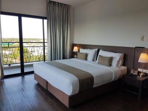 a bedroom with a large bed with a large window at Coco View Hotel in Samut Songkhram