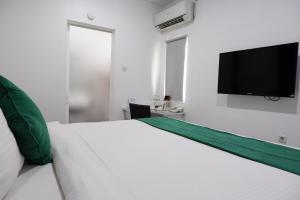 a white bed with a flat screen tv on a wall at Ara Inn Bed And Breakfast by ecommerceloka in Kuta +19 photos