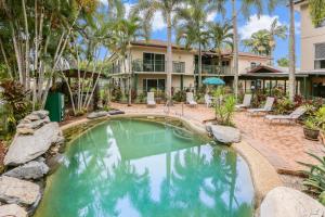 a swimming pool in front of a house with palm trees at Koala Court Holiday Apartments in Cairns
