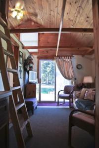 a living room with a ladder and a living room with a couch at Cabin #7 - Northwoods Retreat cabin in Carp Lake