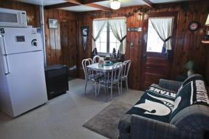 cocina con sofá, mesa y nevera en Cabin #1 - Cedar Village cabin en Carp Lake