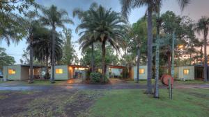 a house with palm trees in front of it at Glenwood Tourist Park & Motel in Grafton