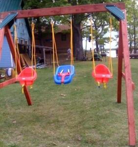 a playground with swings in a yard with a house at Cabin #6 - Casablanca cabin in Carp Lake