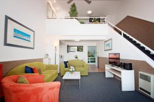 a living room with two couches and a staircase at Sea Spray Motel - Merimbula in Merimbula