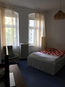 a bedroom with a bed and a chair and windows at Klein App in Alt - Tegel in Berlin