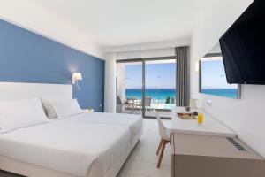a bedroom with a bed and a view of the ocean at Belair Beach Hotel in Ixia