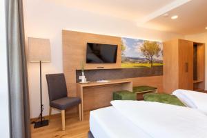 a hotel room with a bed and a desk and a tv at Hotel-Restaurant Gruber in Pöllau