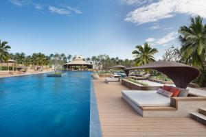 a pool at a resort with benches and umbrellas at Fusion Resort Cam Ranh - All Spa Inclusive in Cam Ranh