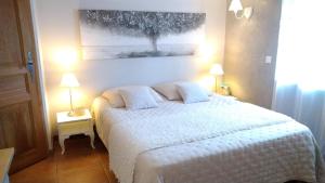 a bedroom with a white bed with a painting on the wall at La Ferme Les Eybrachas in Réauville
