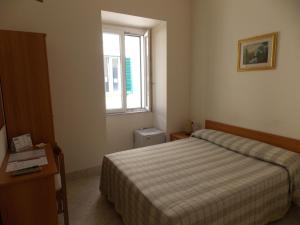 Habitación pequeña con cama y ventana en Albergo Roma, en Matera