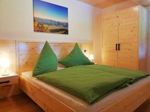 um quarto com uma cama verde e 2 almofadas verdes em Apartment Beim Raffner em Ruhpolding