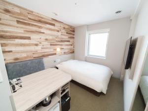 1 dormitorio con 1 cama y pared de madera en Super Hotel Kyoto Shijokawaramachi, en Kioto