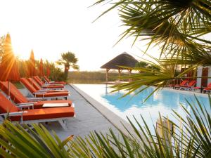 eine Reihe von Liegestühlen neben einem Pool in der Unterkunft Hôtel L' Estelle en Camargue in Saintes-Maries-de-la-Mer