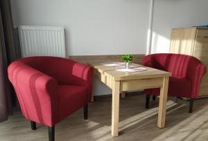 two chairs and a wooden table and a table and two chairs at Tip Top Apartments Kasprowicza in Kołobrzeg