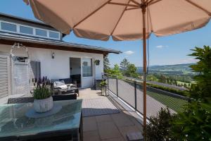 a patio with a table and an umbrella at Heimelig im Allgäu in Lindenberg im Allgäu