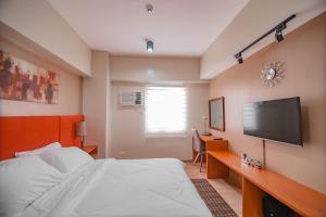 a bedroom with a bed and a flat screen tv at MIGAs Haven at Sunvida Tower across SM City in Cebu City