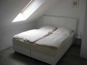 Ce petit lit se trouve dans un dortoir doté d'une lucarne. dans l'établissement Ferienwohnung H. Broschinski, à Aurich