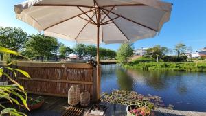 un parasol assis sur une terrasse à côté d'une rivière dans l'établissement B&B Duinbrink, à Le Helder