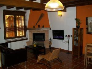 a living room with a fireplace and a tv at El Rincón de la Trilla - La Era in Horcajo de la Sierra