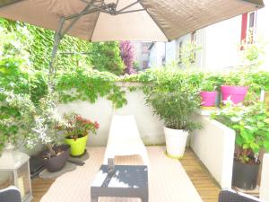 a patio with potted plants and an umbrella at Les Cocons de Stéphanie in Vichy