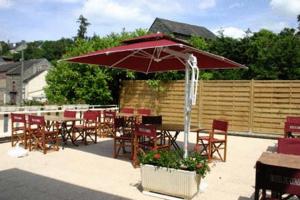 eine Terrasse mit Tischen, Stühlen und einem Sonnenschirm in der Unterkunft Logis Hotel Du Commerce in Pont-d'Ouilly