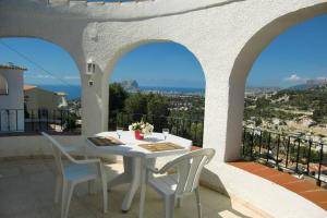 ein weißer Tisch und Stühle auf einem Balkon mit Aussicht in der Unterkunft Casa León with private pool great view in Benissa