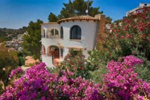 ein Haus auf einem Hügel mit Blumen davor in der Unterkunft Casa León with private pool great view in Benissa
