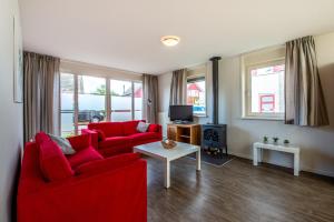 ein Wohnzimmer mit zwei roten Sofas und einem TV in der Unterkunft Maxime 207 - Kustpark Village Scaldia in Hoofdplaat