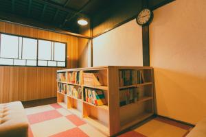 a room with a book shelf with books and a clock at guesthouse絲 -ito-ゲストハウスイト in Fukumitsu