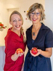 two women standing next to each other holding apples at Hotel Eikamper Höhe in Odenthal