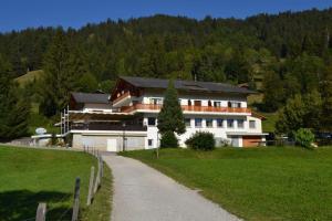 ein großes weißes Haus auf einem Hügel mit einer Straße in der Unterkunft Hotel Bad Schwarzsee in Bad-Schwarzsee