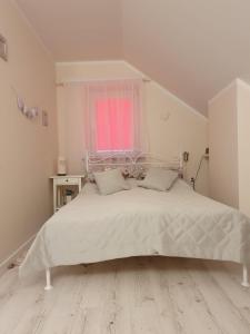 1 Schlafzimmer mit einem weißen Bett und einem rosa Fenster in der Unterkunft Hotel Wojto in Zamość