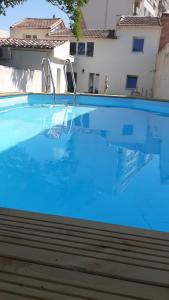 une grande piscine bleue en face d'un bâtiment dans l'établissement Maison trois chambres, près remparts, jardin, piscine, à Avignon