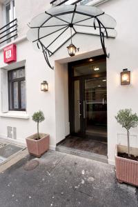 an entrance to a building with two trees in front at Hipotel Paris Père-Lachaise République in Paris