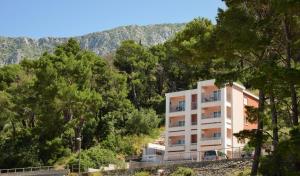 a white apartment building in the middle of trees at Villa Stina Drvenik in Drvenik