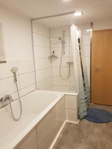 a white bathroom with a shower and a tub at Ferienwohnung Schwabendorf - nahe Marburg in Rauschenberg +9 photos