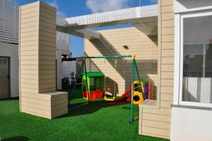 einen Spielplatz in einem Haus mit grünem Gras in der Unterkunft Sol y Sombra in Benidorm