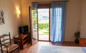 a bedroom with a television and a sliding glass door at Hotel Cortijo de Salia in Alcaucín