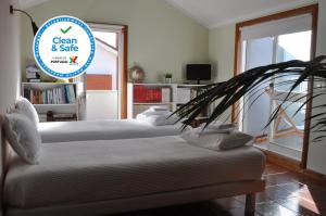 - 2 lits dans une chambre avec un panneau indiquant « propreté et sécurité » dans l'établissement SUN & SAND GUESTHOUSE, à Esposende