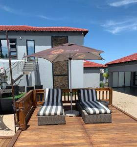 2 chaises et un parasol sur une terrasse en bois dans l'établissement The Farm Boutique Guest House, à De Hoop